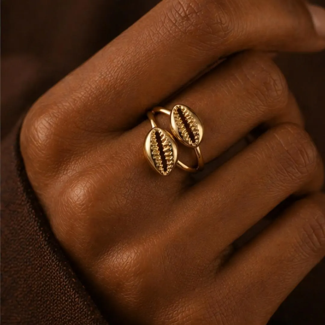 Bague coquillage cauri dorée portée au doigt — Cissey Clothing